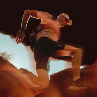 Trail runner climbing rocky terrain in dramatic warm lighting, wearing Salomon gear, for Early Access to Big Spaces campaign.