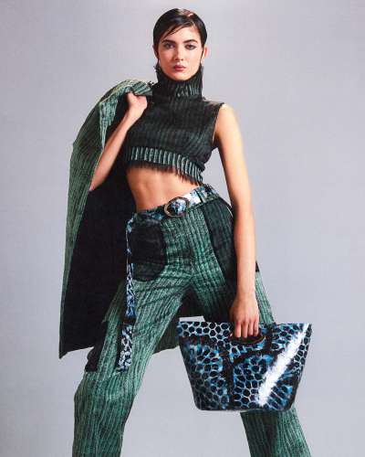 Model wearing Lora Sonney Soleil Brûlant collection, featuring textured green knit ensemble and experimental material accessories with bold pattern.